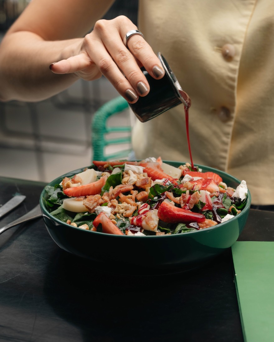 Ensalada con camarón y jitomate mientras le sirven la vinagreta