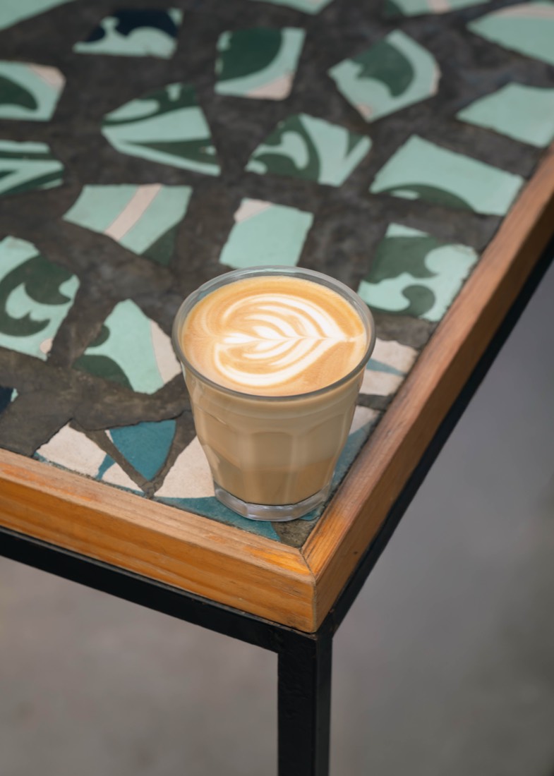 Flat White con arte latte sobre una mesa de mosaico