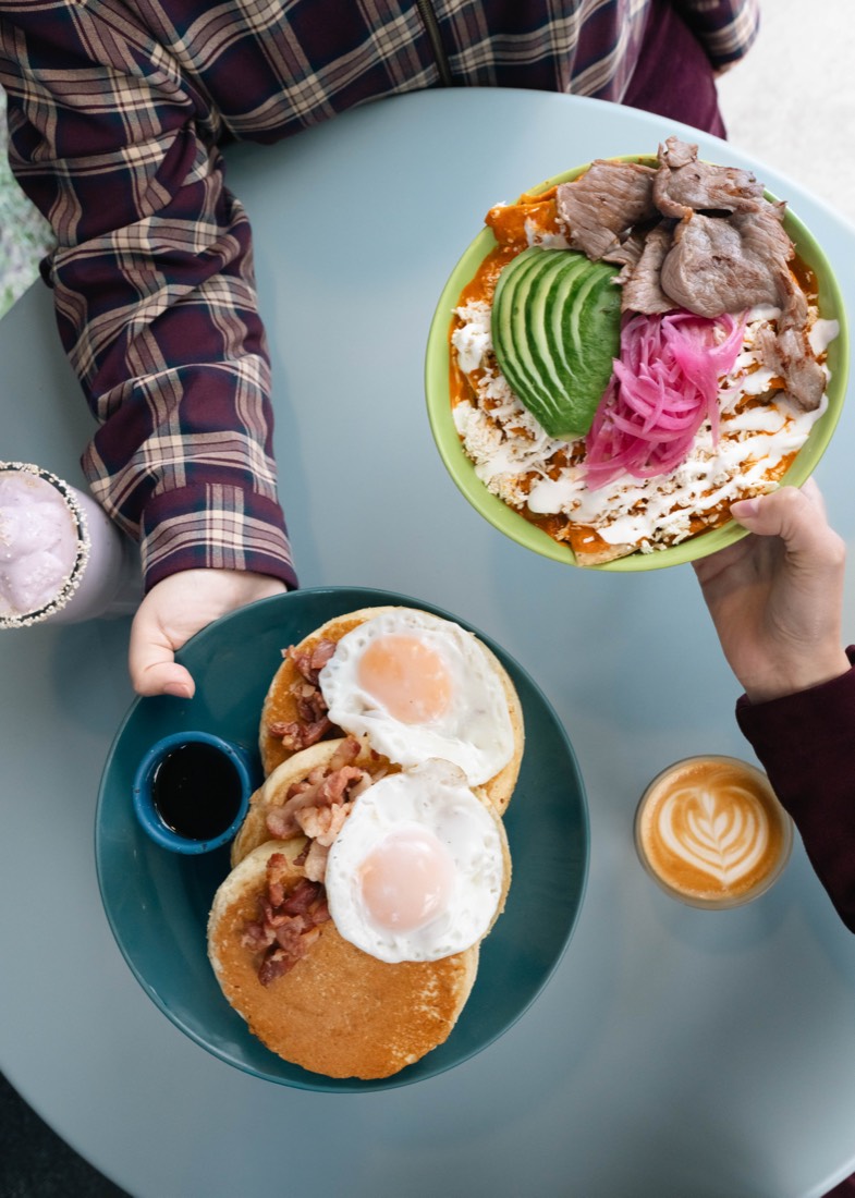 Hotcakes con tocino y huevo estrellado, vistos desde arriba junto a un café