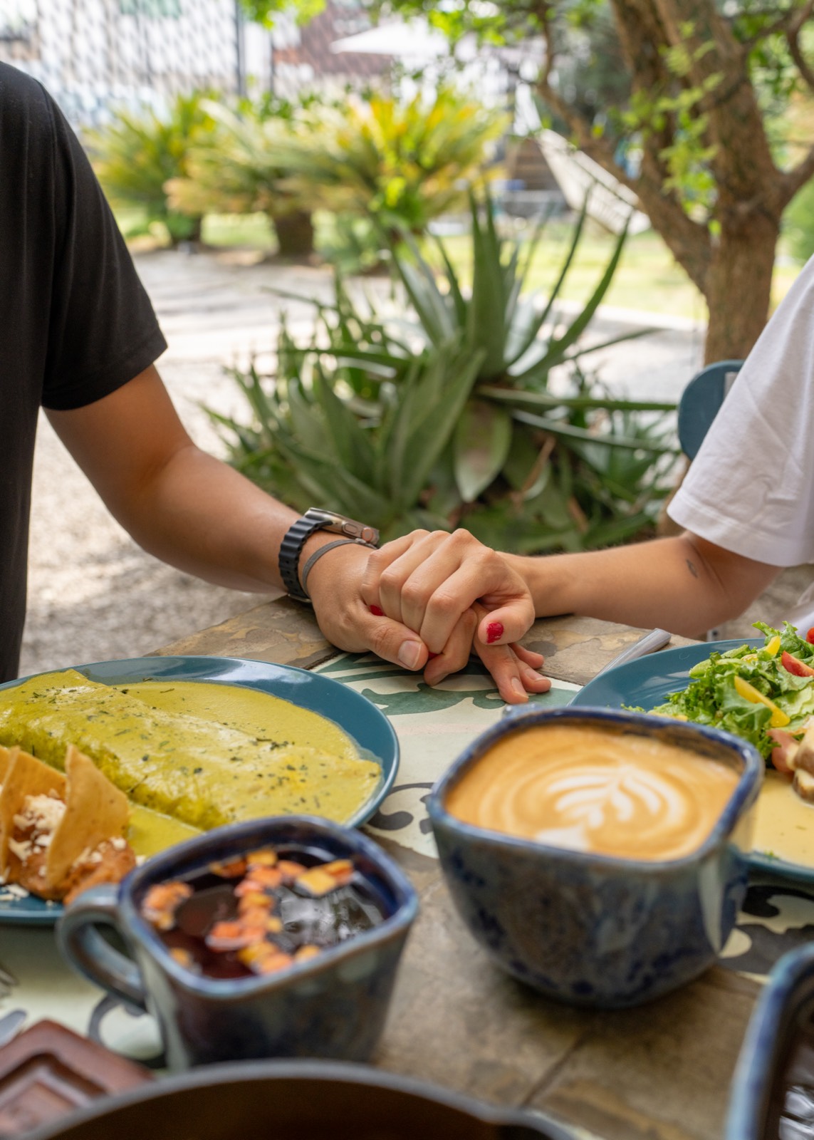 Dos personas tomadas de la mano sobre una mesa con desayuno y café