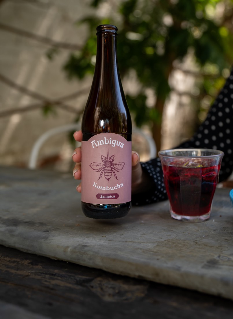 Botella de kombucha Ambigua junto a un vaso servido sobre una mesa de piedra
